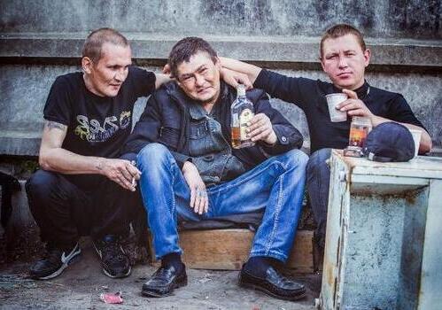 Трое мужчин сидят под забором